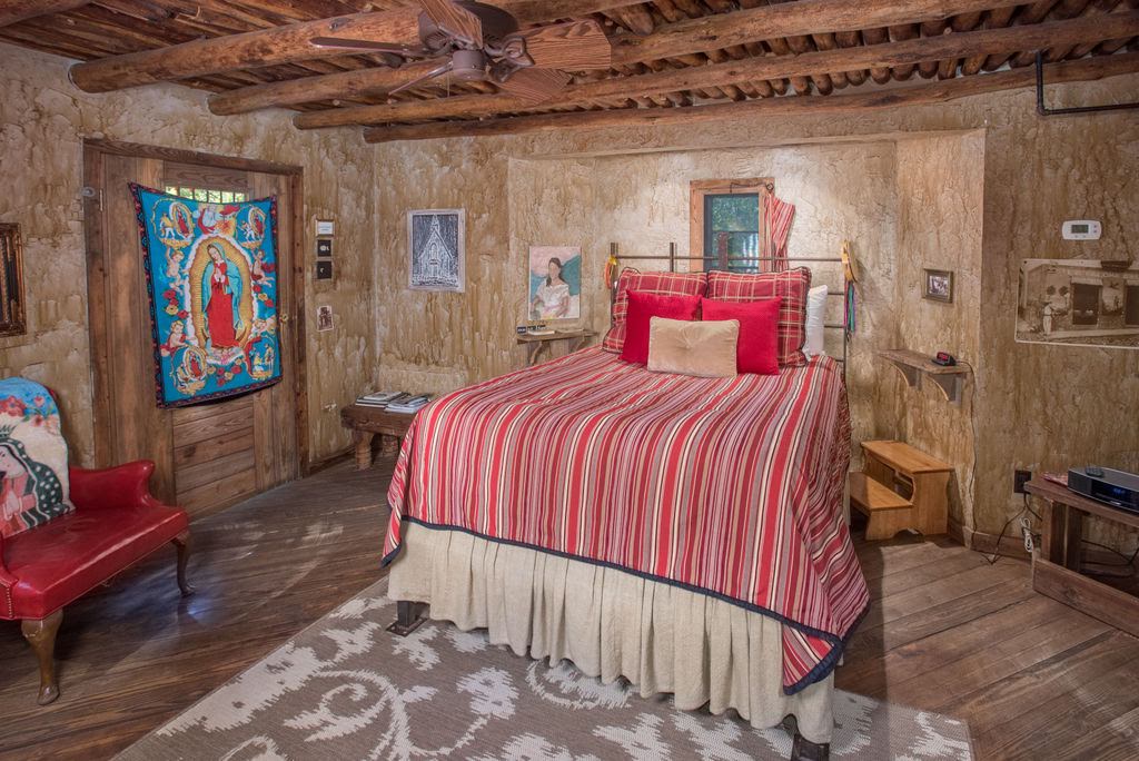 Mexico Cabin photo with traditional Mexican decor and an Adobe Feel while pops of red from the chair and pillows on the bed lined with a red and yellow striped blanket bring a sense of color to the room - Texas Bed and Breakfast
